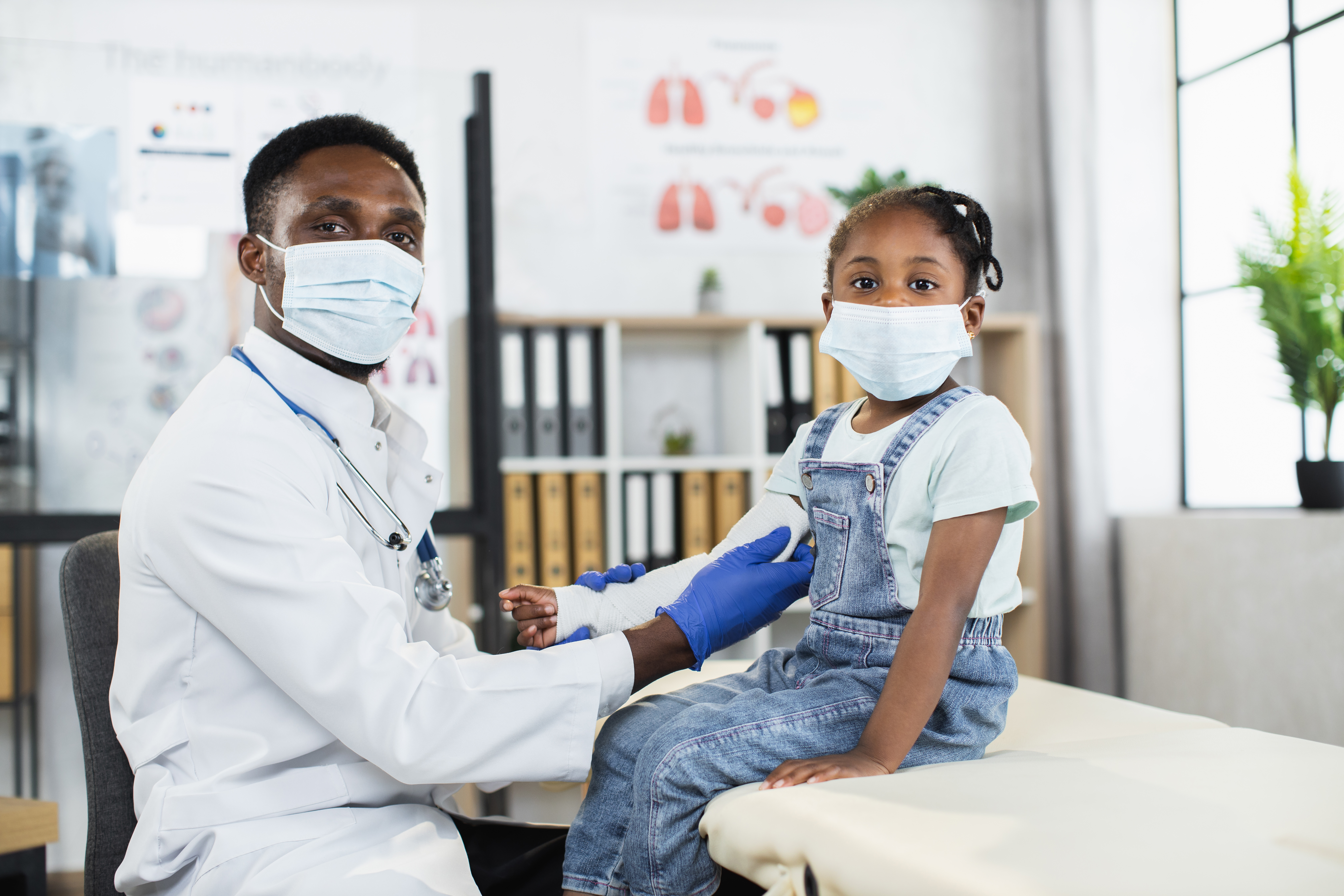 Black doctor changing bandage on arm of little girl